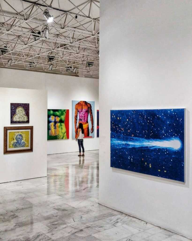 Gallery showcasing diverse contemporary art pieces with an observer in view.