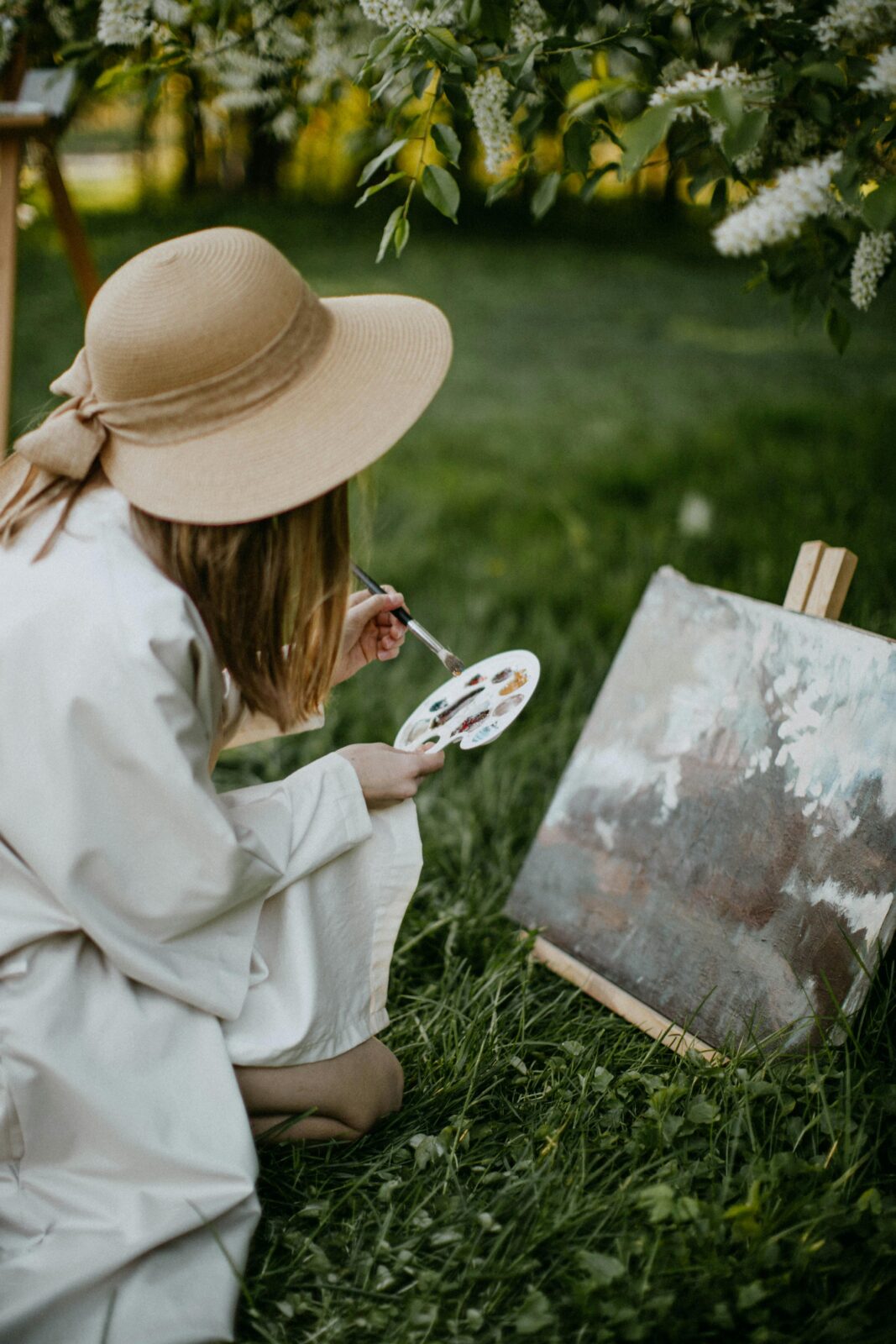 Young woman painting in a lush garden, capturing nature's beauty in spring.