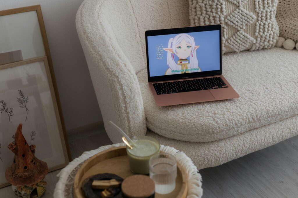 A comfortable living room setup featuring a laptop displaying an anime character on a plush sofa.
